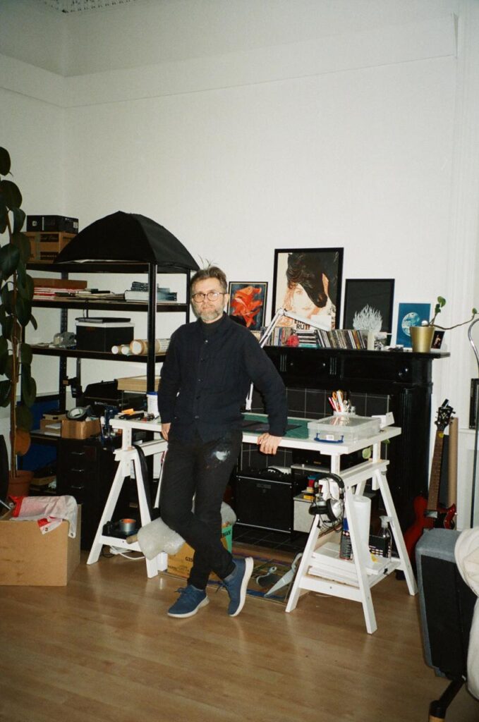 Wojtek in his studio, with the back against the desk, the photo is on film and looks very 90s