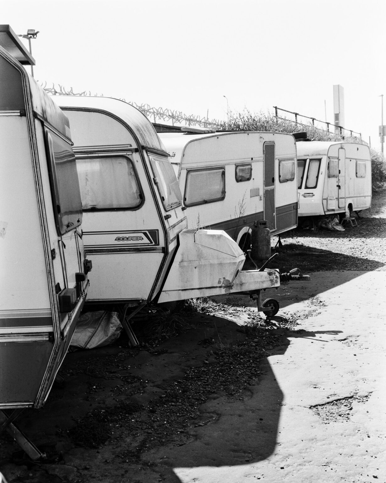 Black and white photograph of sad-looking camping trailers in storage
