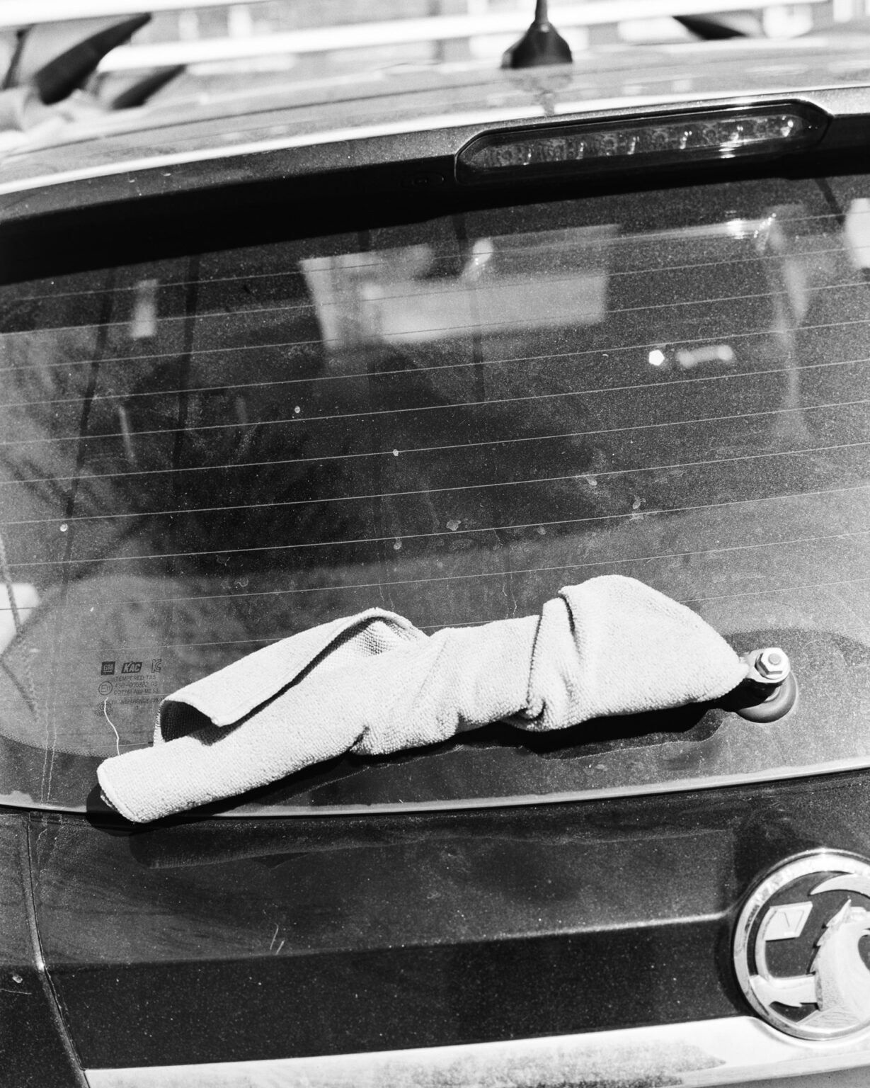 Black and white image of a towel on the car's back windscreen wiper