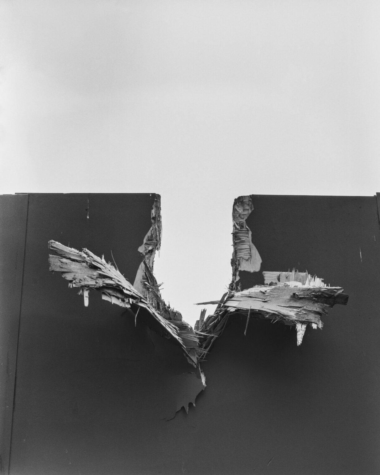 Black and white photograph of a hole in the wall that looks as if it was created by a cannonball