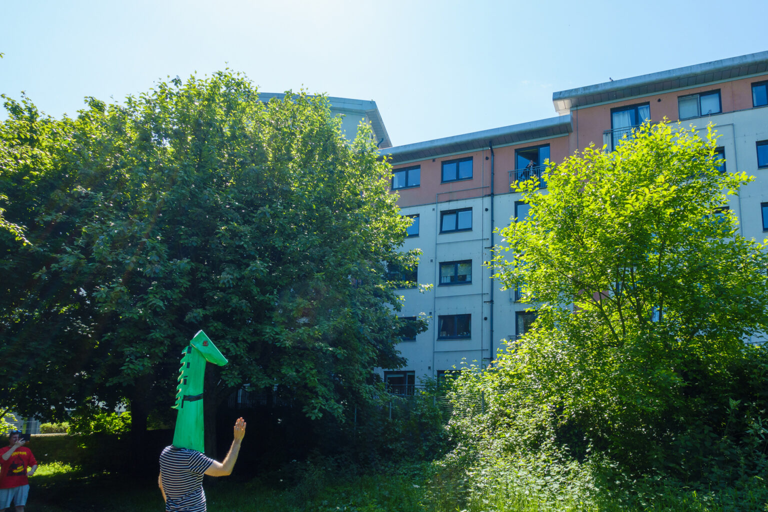 Wojtek dressed as the Nessie monster, waving to the person in the window