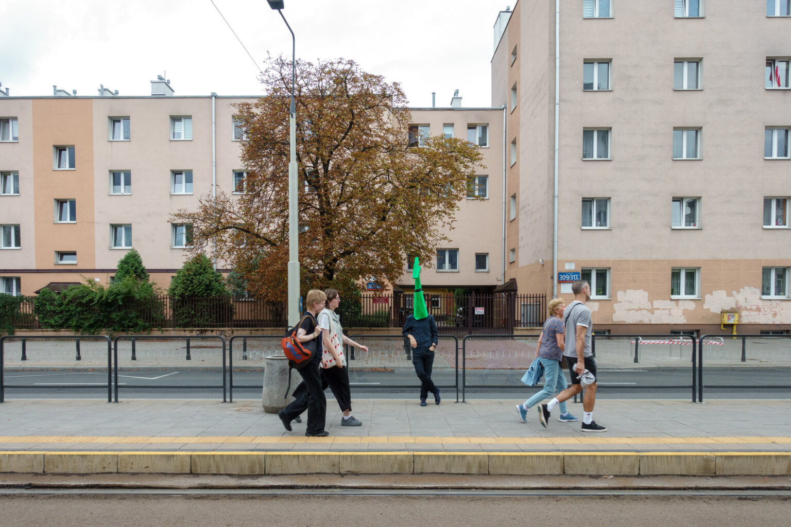 Wojtek as a monster with passers-by on a tram stop in Warsaw