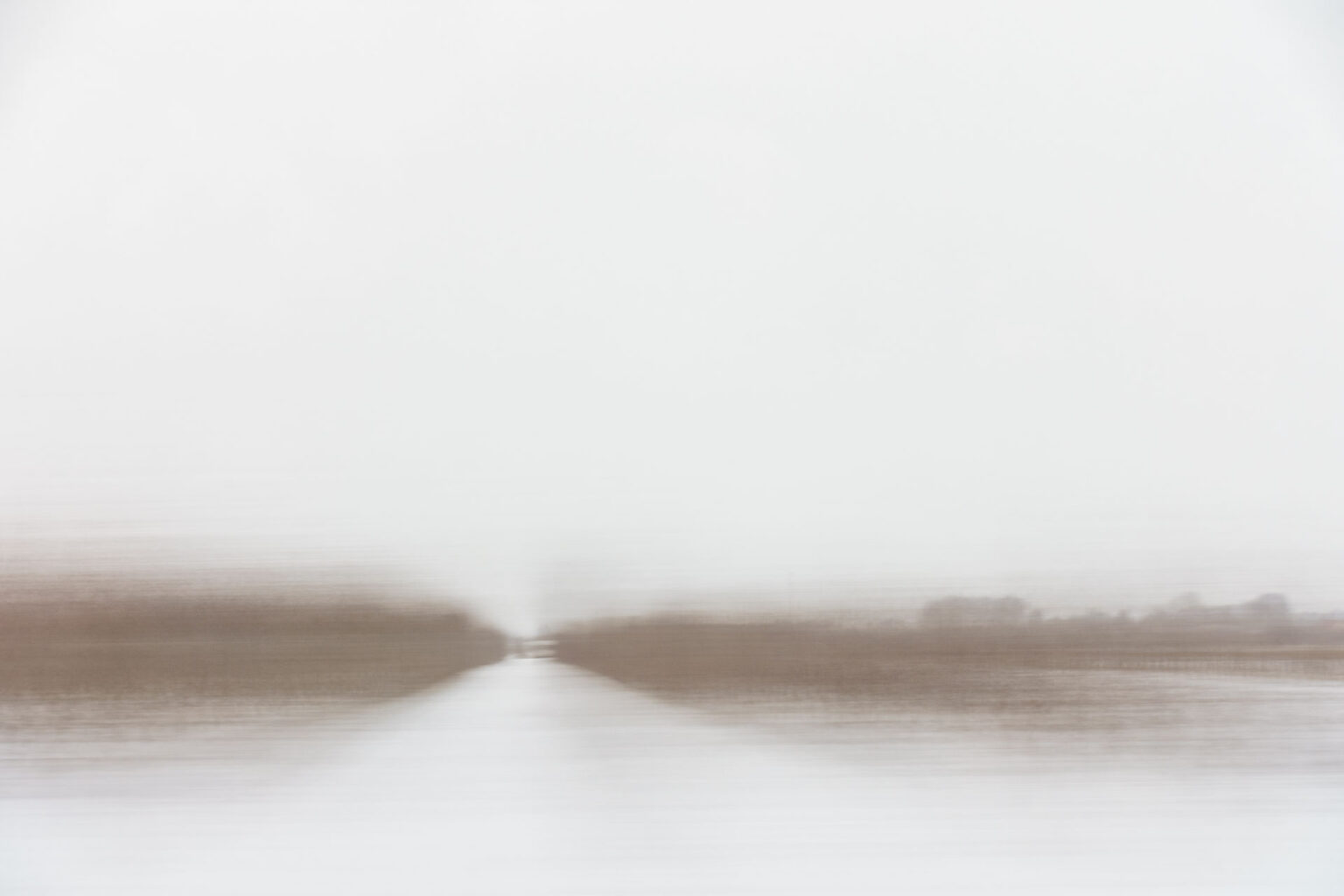 A blurry landscape image shot through a window on a moving train