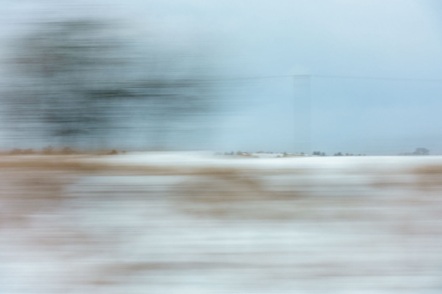A blurry landscape image shot through a window on a moving train
