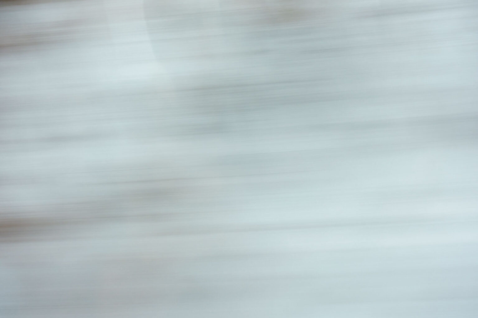 A blurry landscape image shot through a window on a moving train