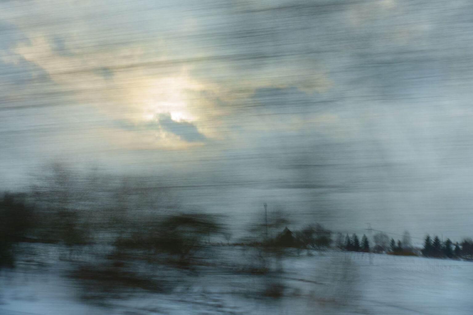 A blurry landscape image shot through a window on a moving train
