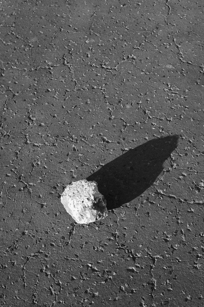 Photograph of a stone that looks like a meteorite, casting a strong shadow