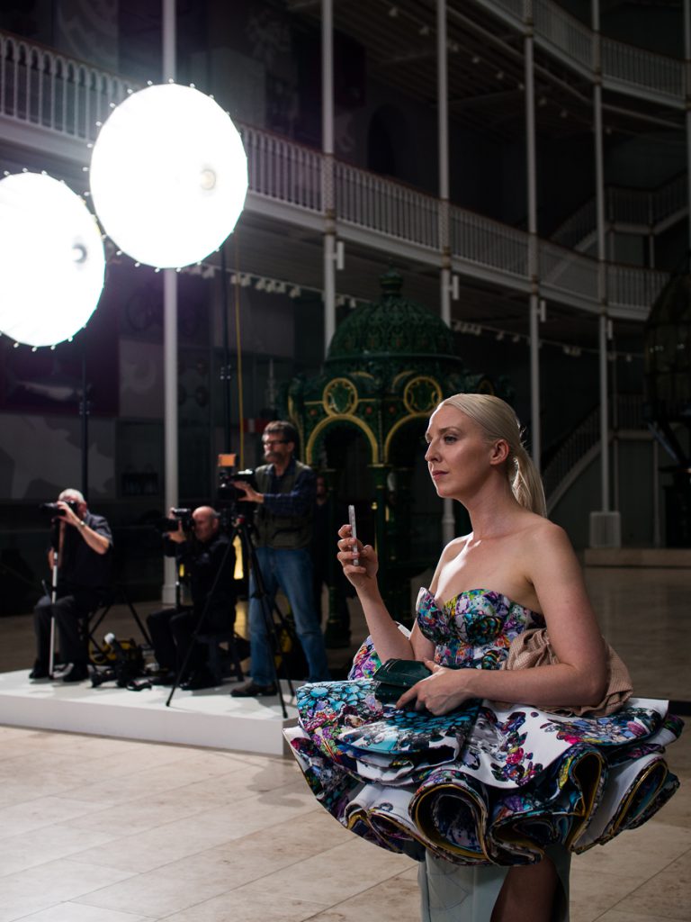A woman in an extravagant dress filming the show with her mobile