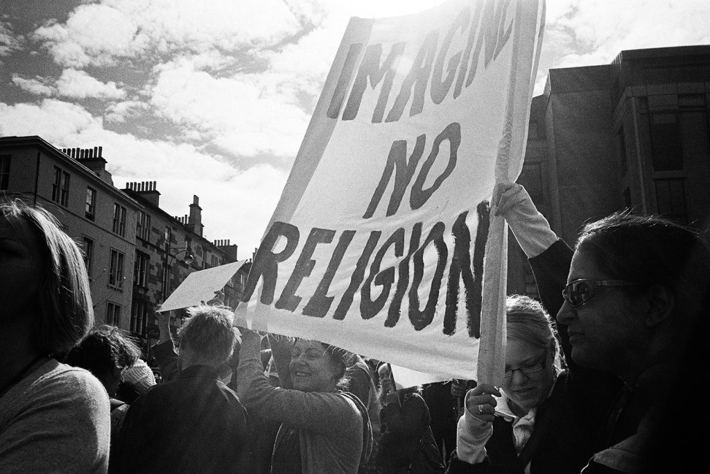 Photograph of a demonstration crowd. People holding Imagine no religion sign.
