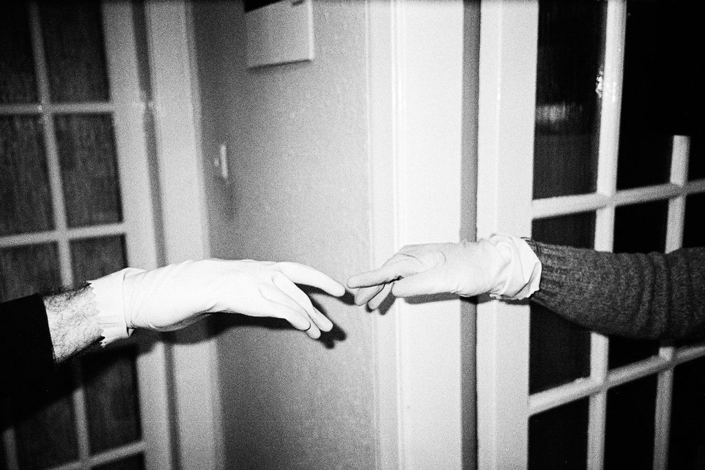 Photograph of two hands, making a mock-up of a gesture of David and God, wearing working gloves.