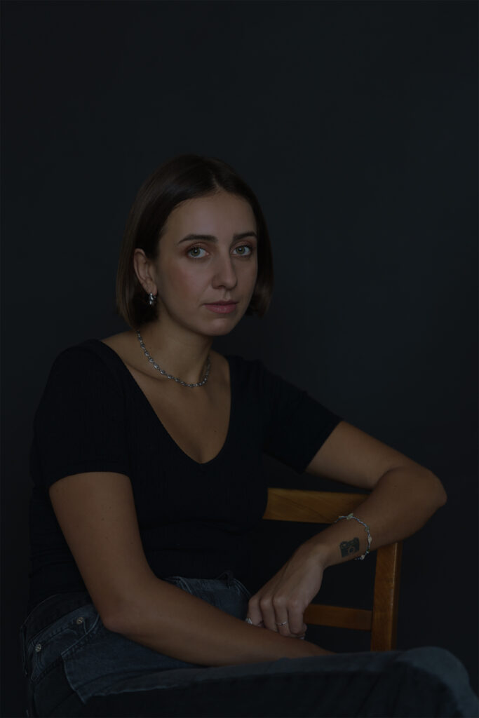 Natalia sitting on the chair in the studio. Low light. She's very peaceful.